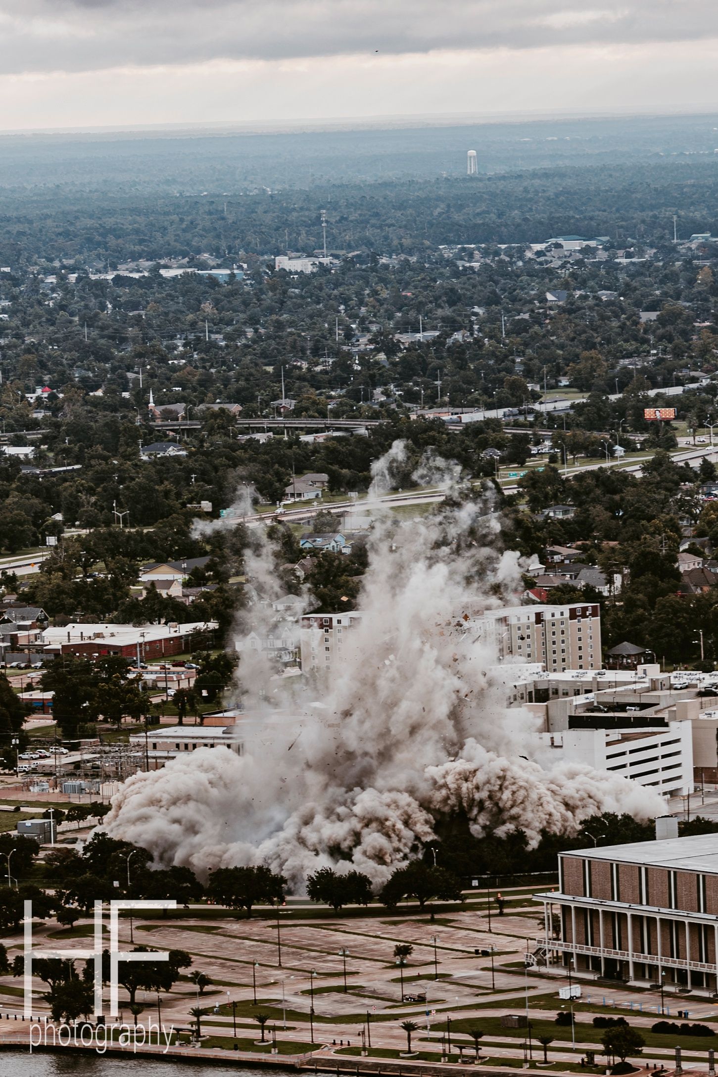 Urban demolition sequence showing building collapse and dust cloud spreading across city landscape.