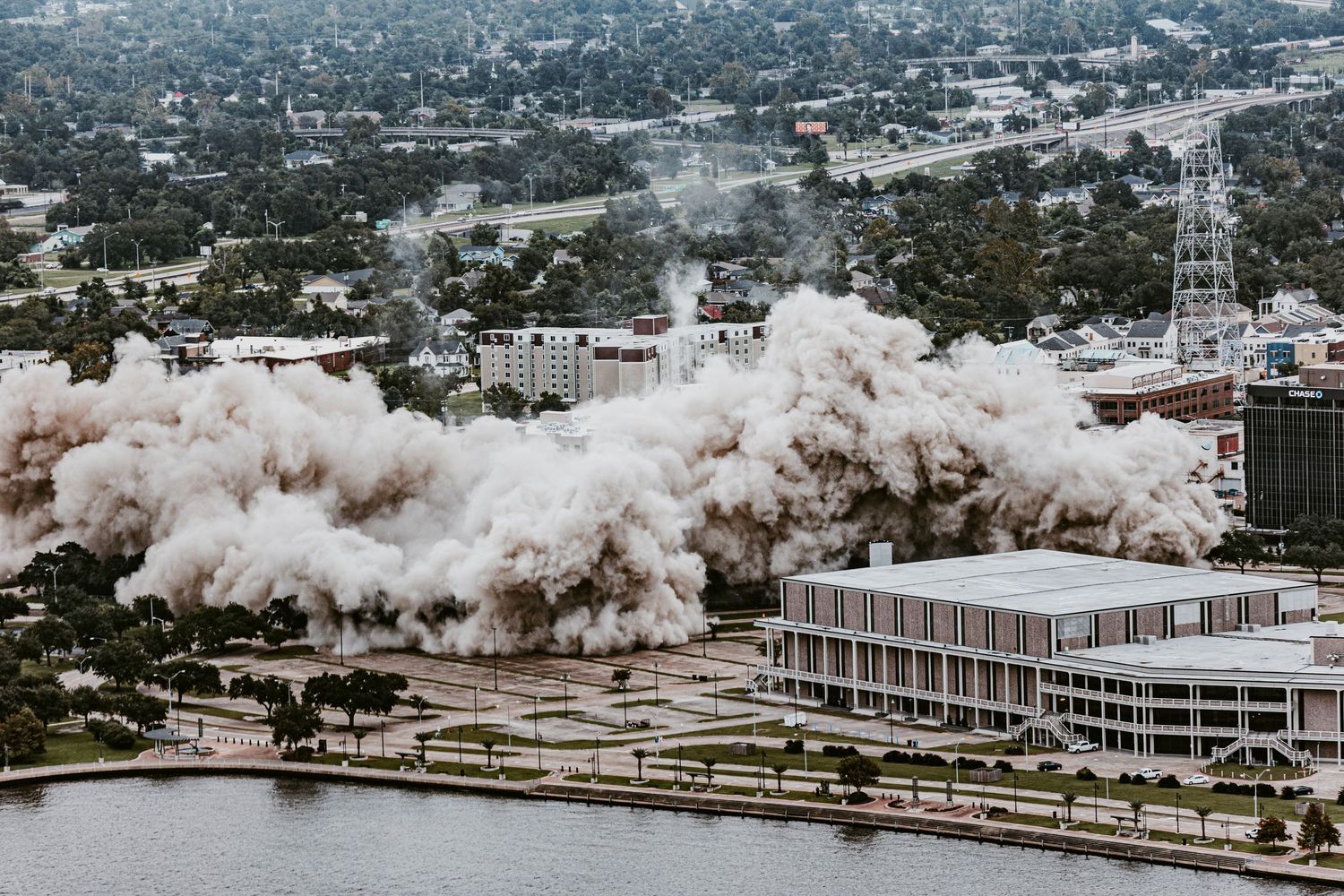 Sequence of building implosion creating massive dust cloud in city center.