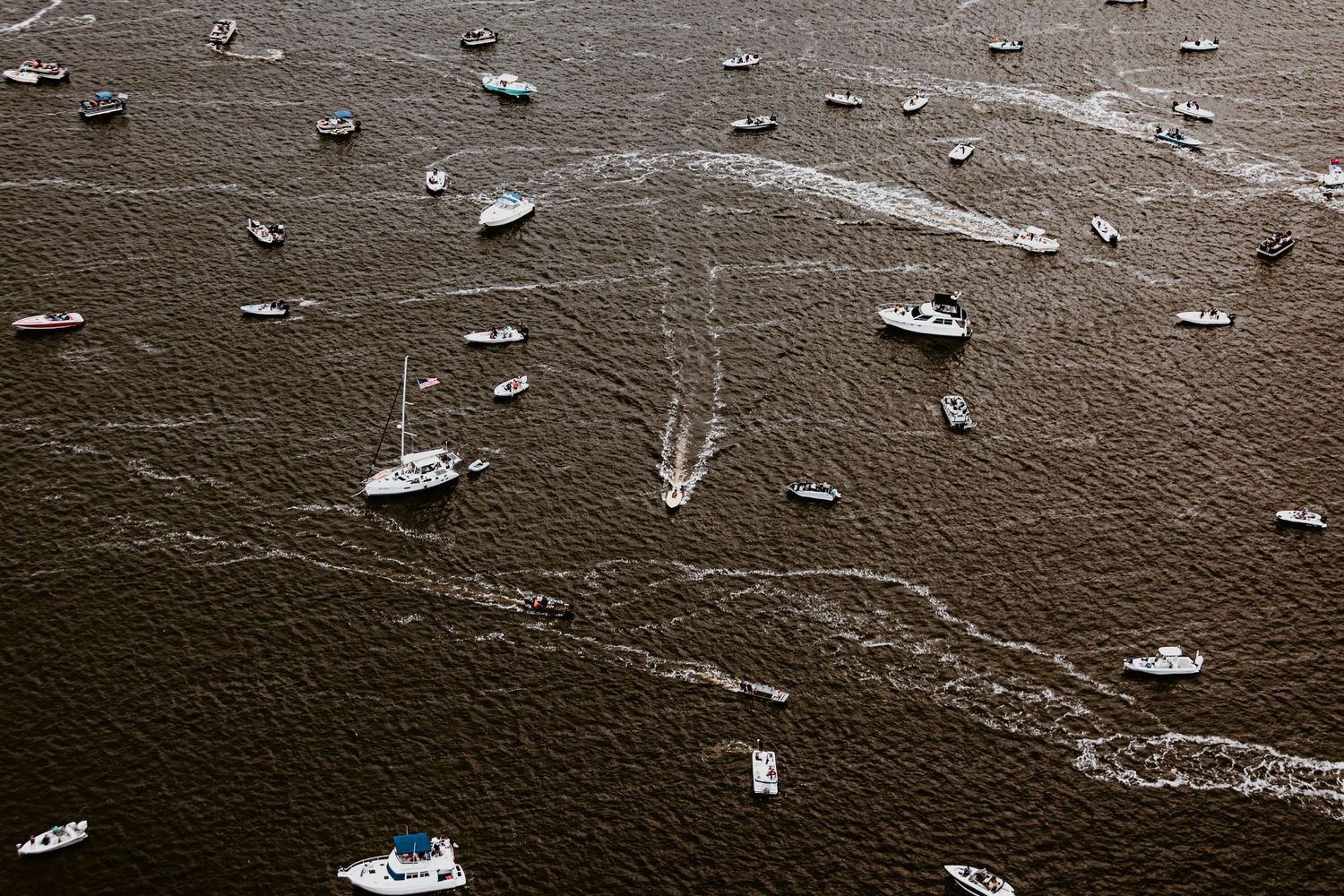 Black and white aerial view of boats scattered across harbor waters.