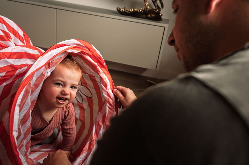 A playful moment with red and white striped blankets creating a cozy fort.