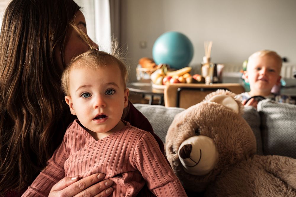 Intimate indoor portrait with soft lighting and a plush teddy bear in the background.