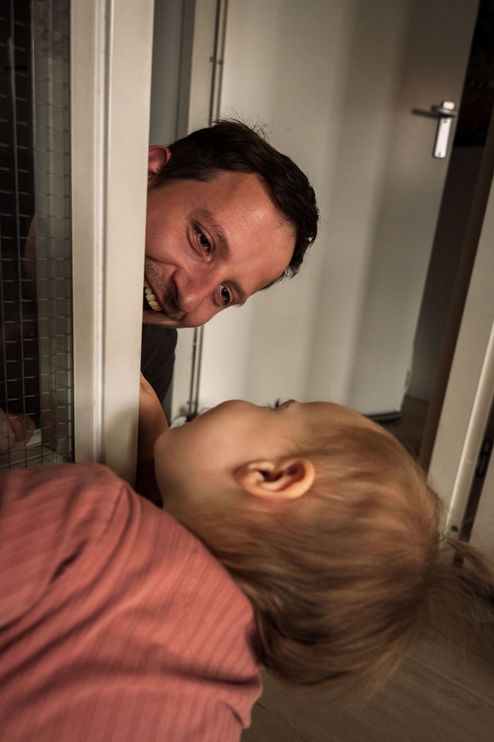 A tender moment of play and connection through a doorway.