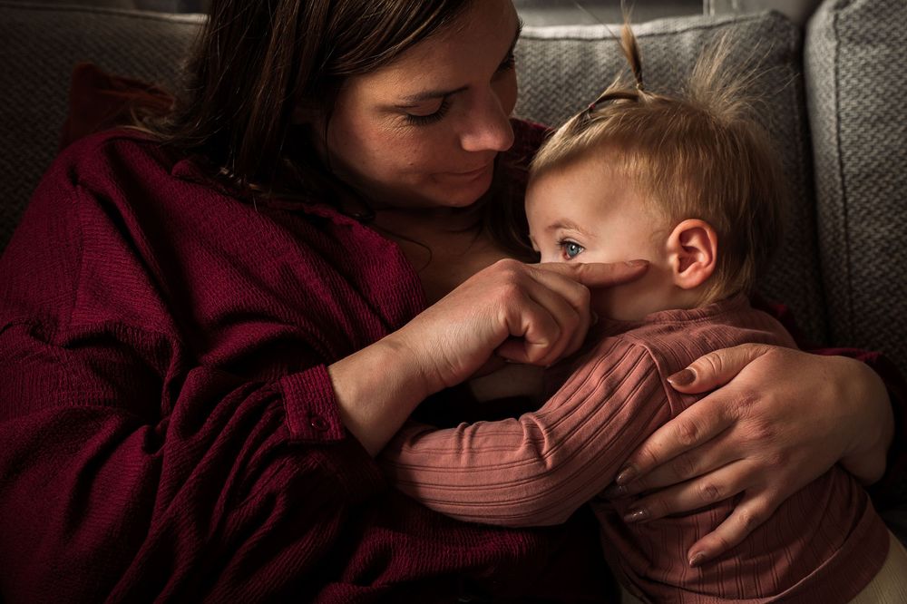 Tender moment captured in burgundy tones with soft indoor lighting.