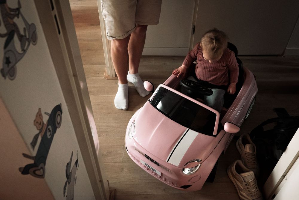 Pink toy car being played with in a home setting.