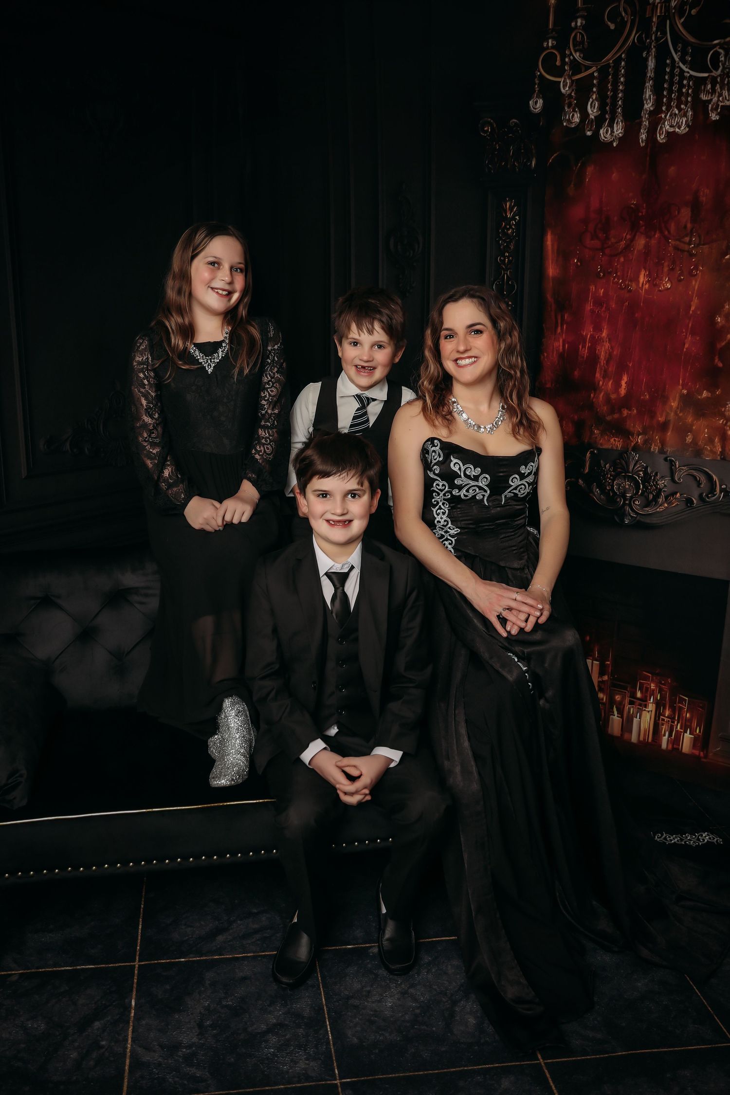 Family group poses together in formal attire at an elegant dark venue with red accent lighting.