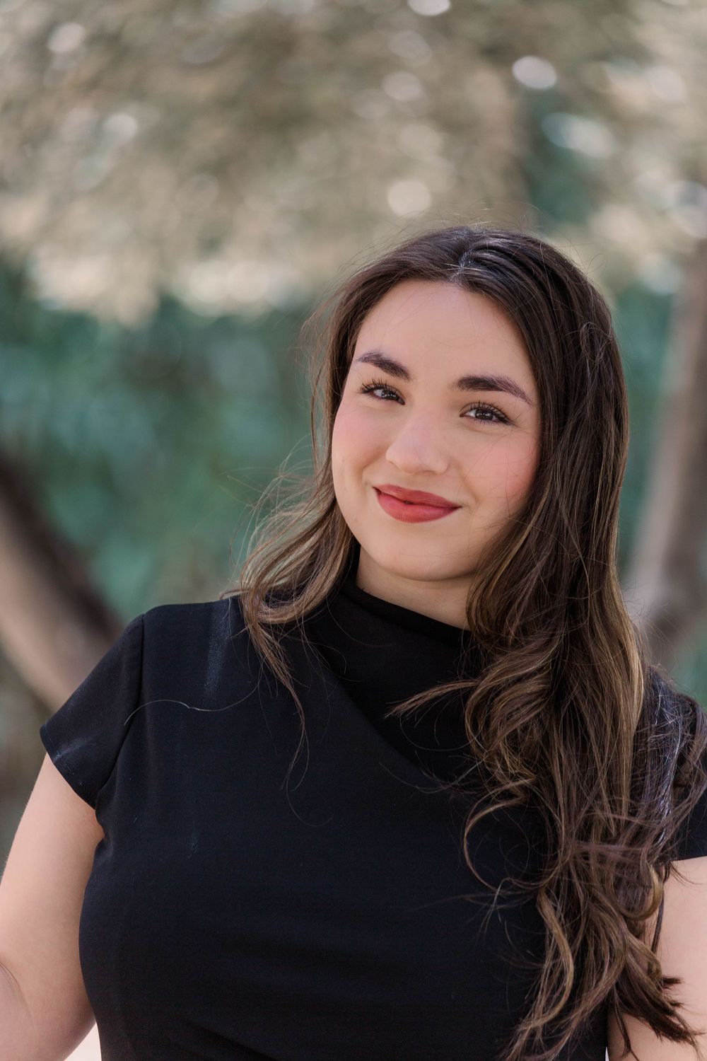 Casual outdoor portrait with natural lighting featuring a black top and joyful expression.