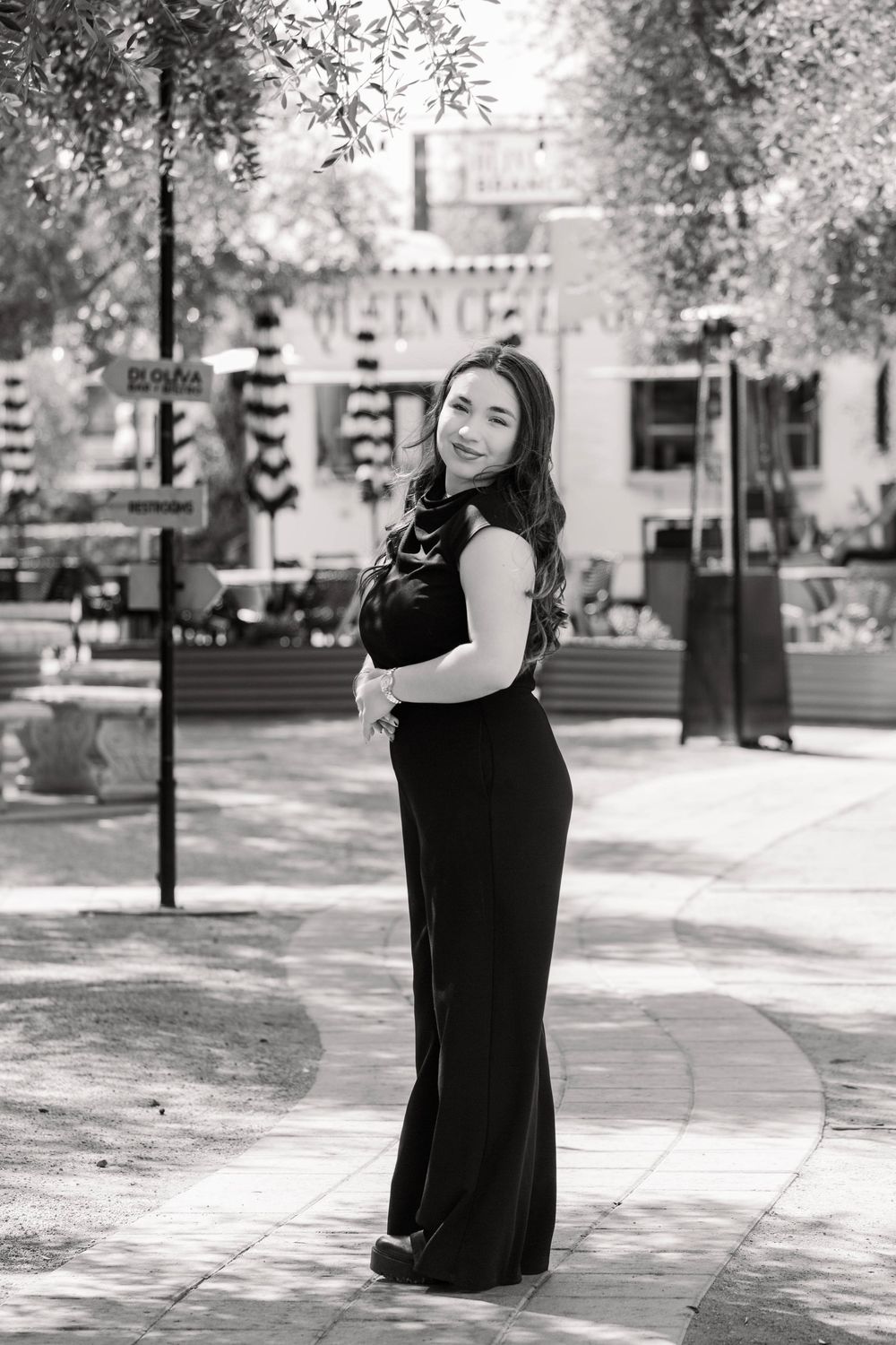 A series of black and white outdoor portraits showing a person in a sleeveless black dress standing on a paved walkway.