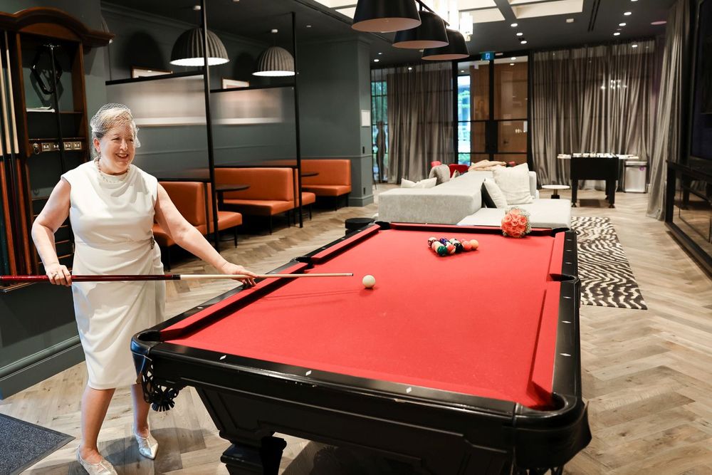 A game room features a red pool table where someone is playing billiards.