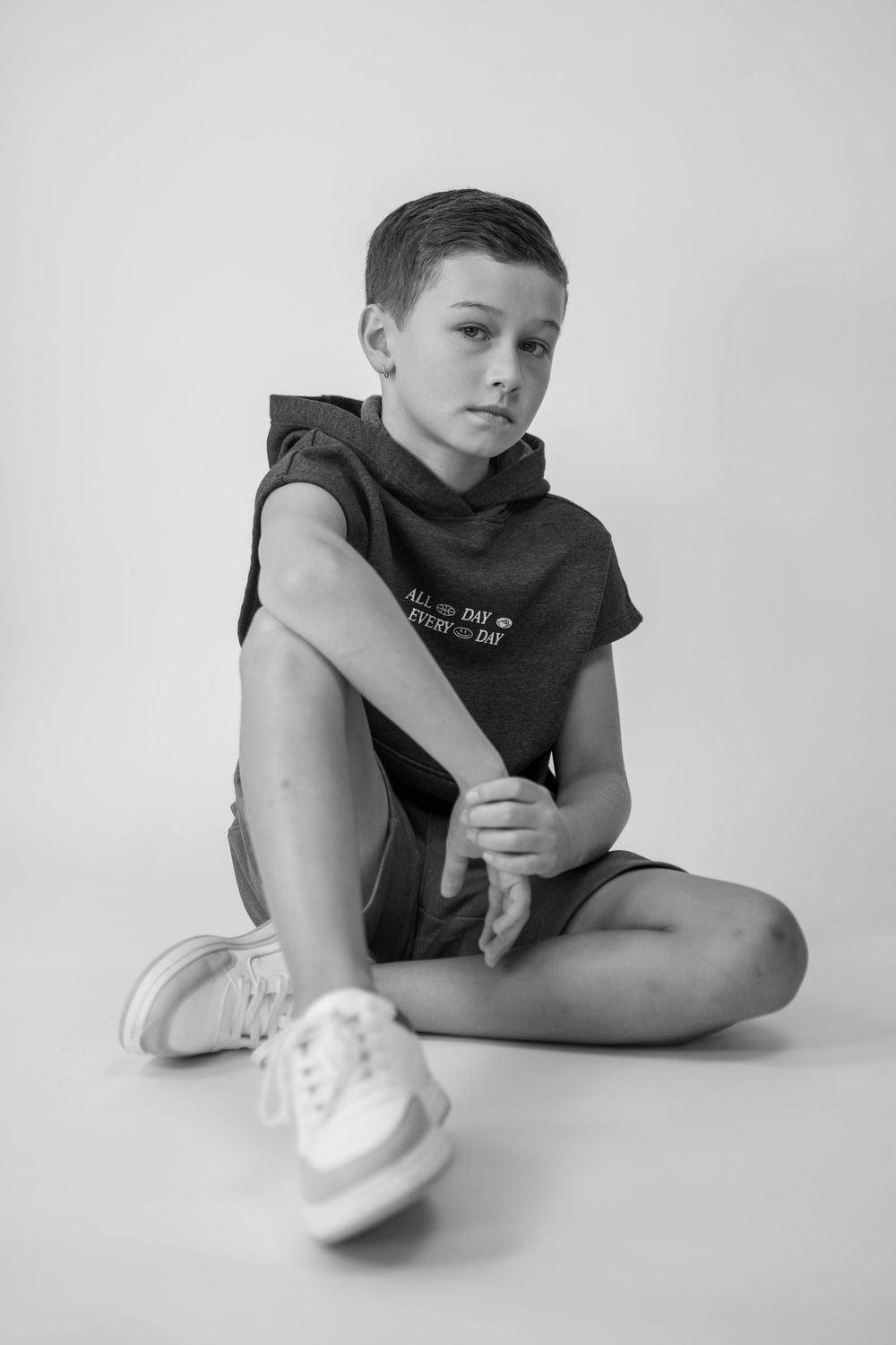 A black and white photo series shows someone in a dark shirt posing with white sneakers against a light background.