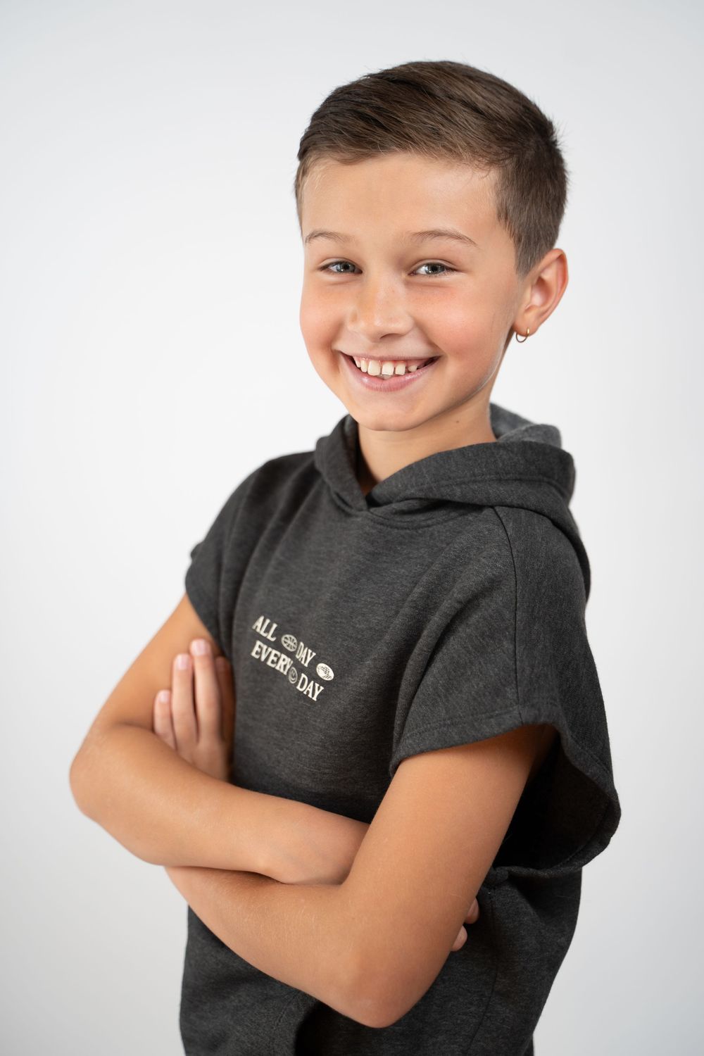 Young model in dark gray hoodie showcases multiple playful poses against white background.