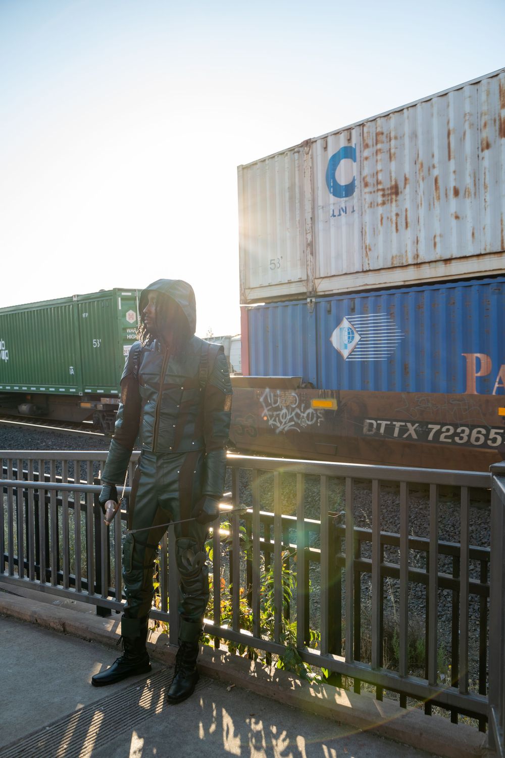 Outdoor photoshoot against shipping containers in warm sunlight showing urban industrial aesthetic.