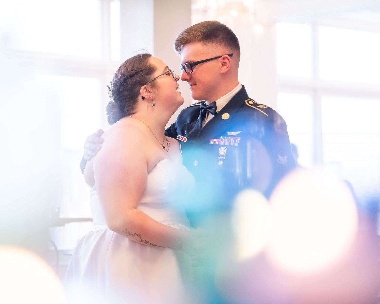 A loving couple shares a tender moment in their first dance on their wedding, with the groom wearing a military dress uniform.