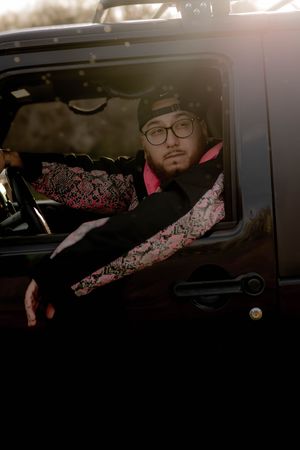 Person napping across back seats of car interior wearing pink cat ear headphones.
