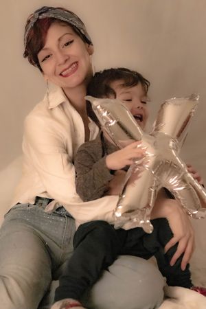 A cheerful moment holding a metallic silver letter X balloon while sitting together in casual attire.