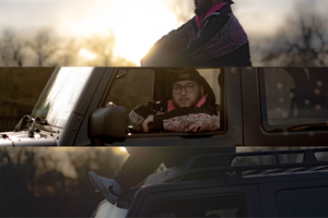 Silhouette of car interior against sunset sky with person reclining in back seat.