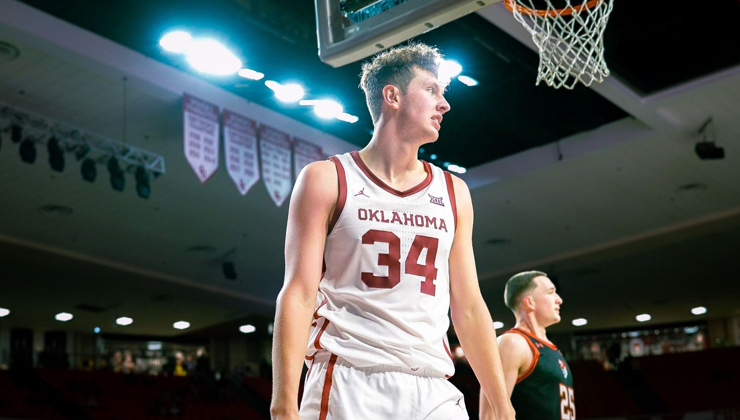 Oklahoma basketball player wearing number 34 white jersey stands on court during game.