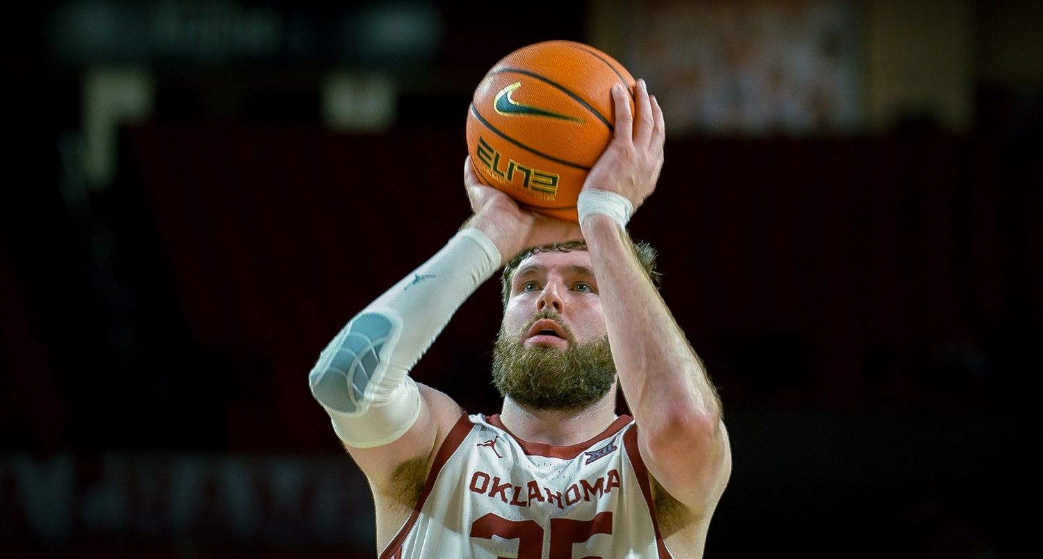 Basketball player in red and white jersey taking a shot during a competitive game.