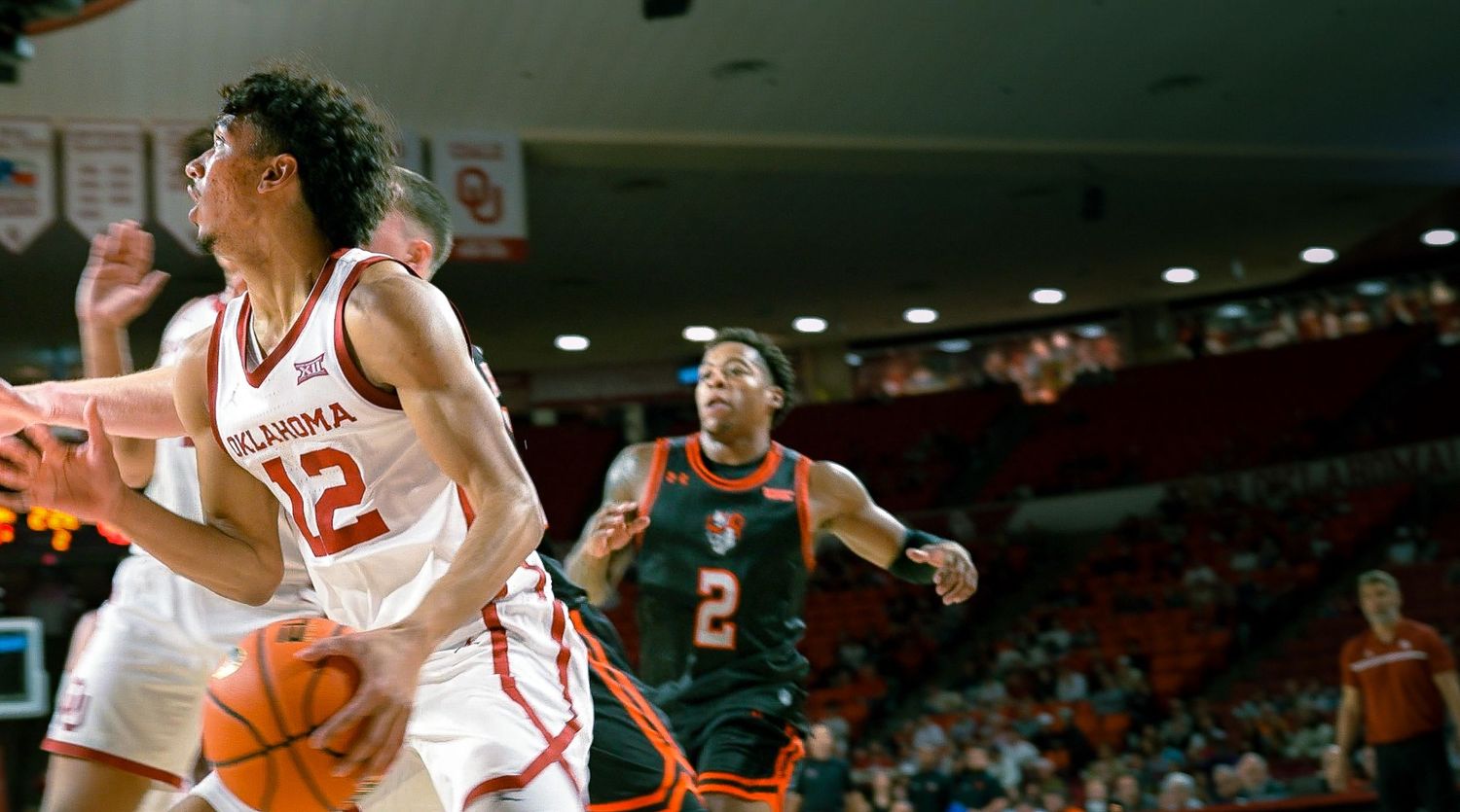 Basketball players compete for possession during an intense Arkansas college basketball game.