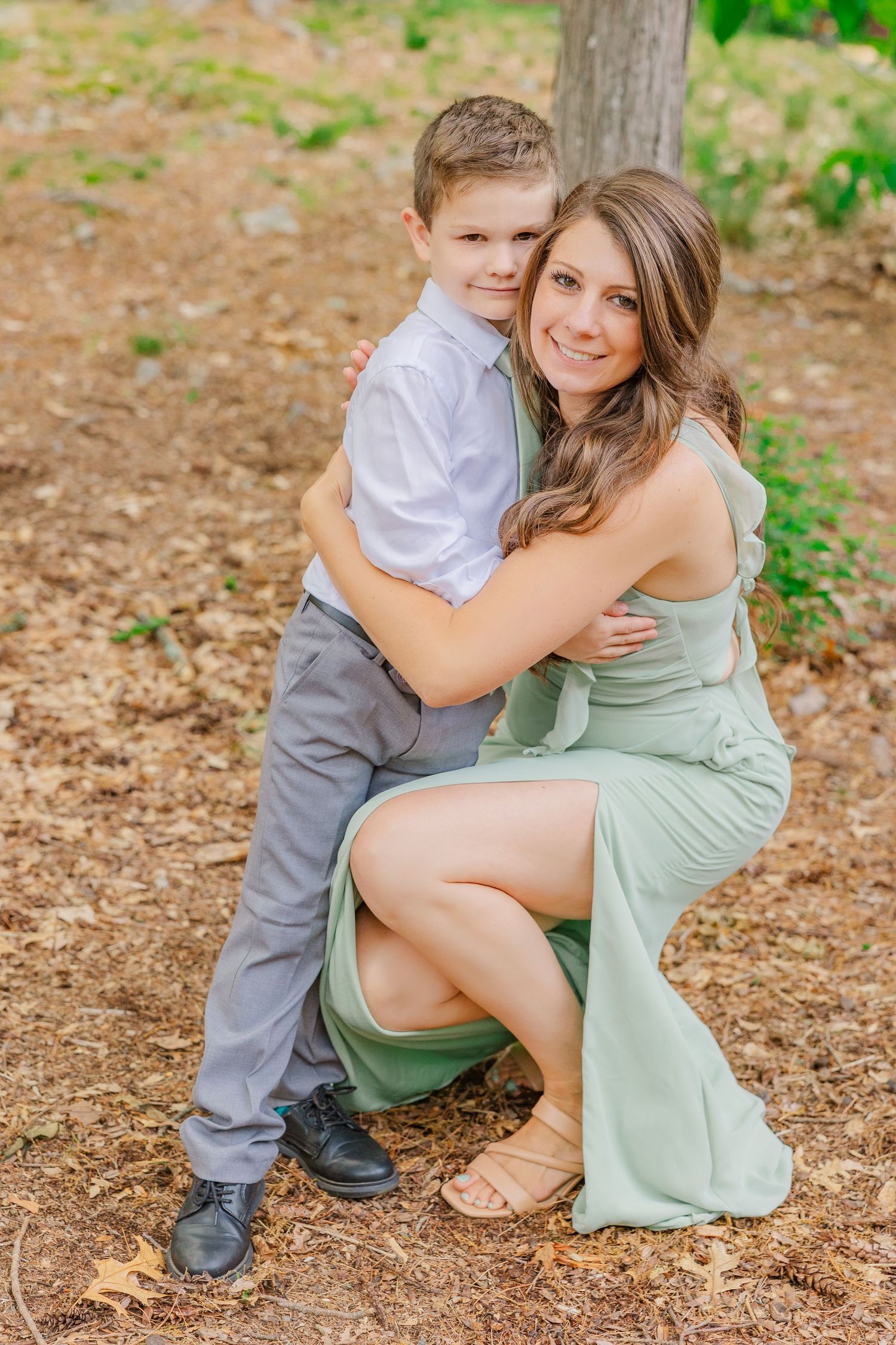 A tender outdoor portrait of a parent and child hugging while wearing coordinating light green and gray outfits.