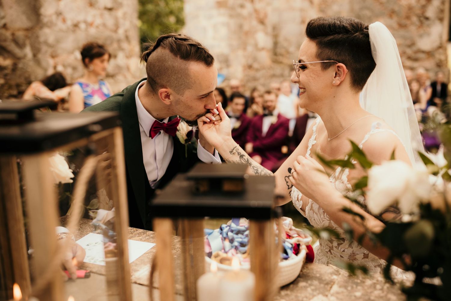 Playful wedding moment shared during outdoor reception with guests in background.