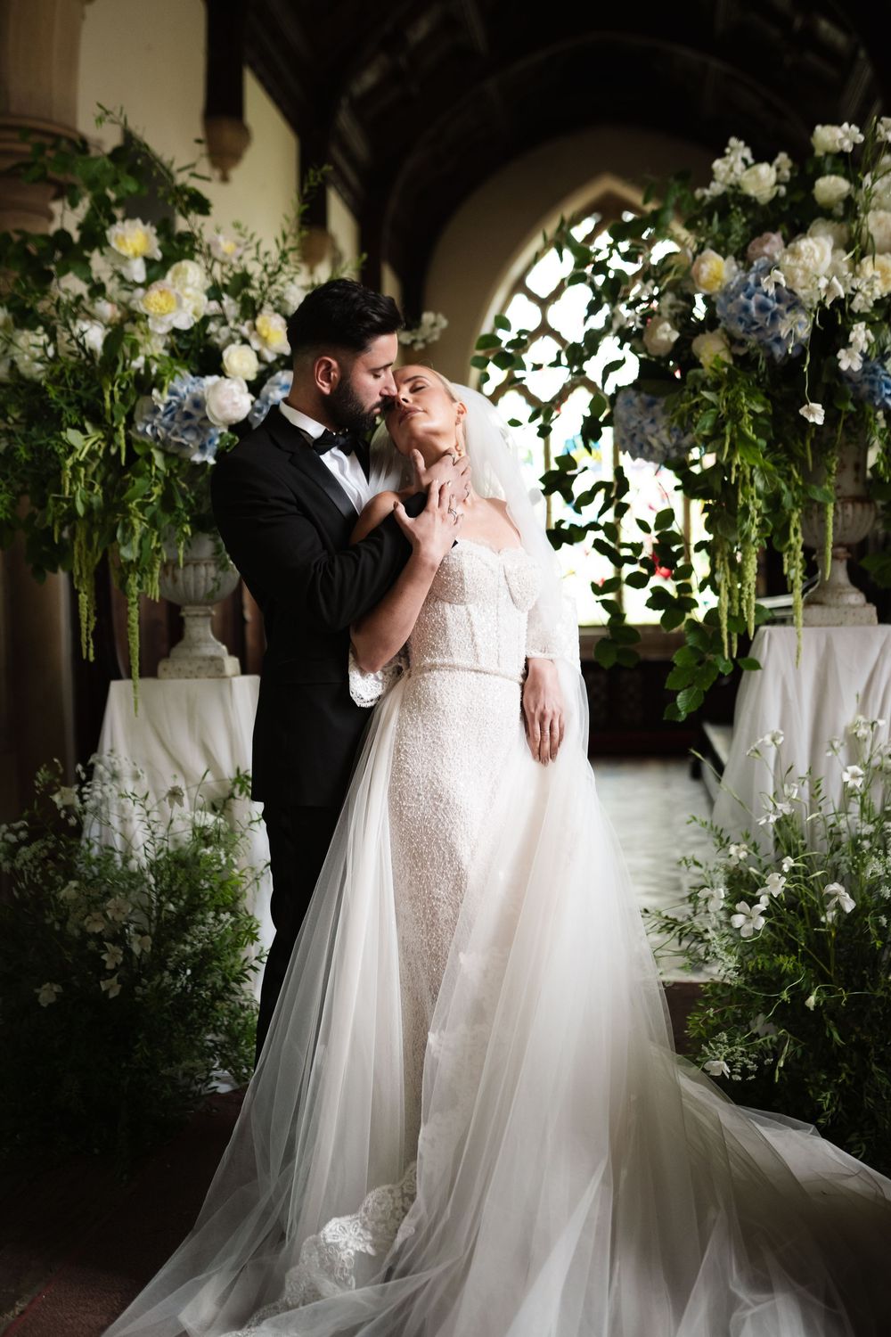 Wedding couple sharing an intimate moment under soft lighting with floral arrangements.