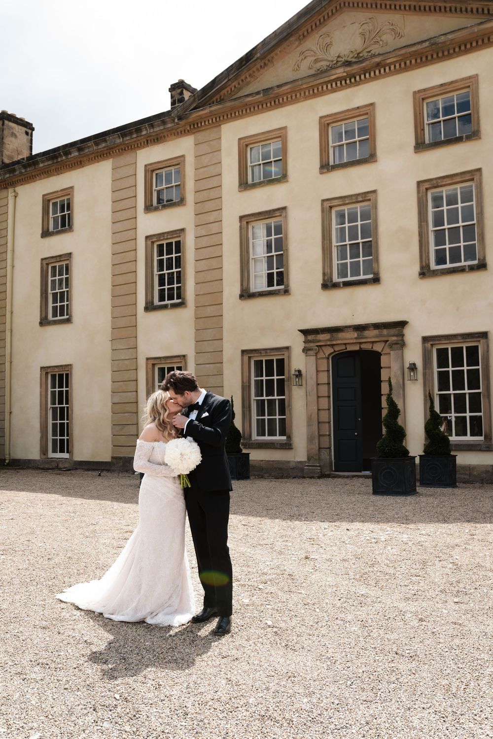 Wedding portraits on the grounds of a stately Georgian-style building with gravel courtyard.