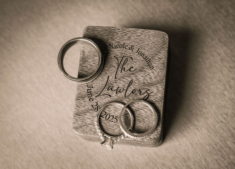 Wedding rings resting on top of a vintage save the date invitation card in a sepia tone photograph.