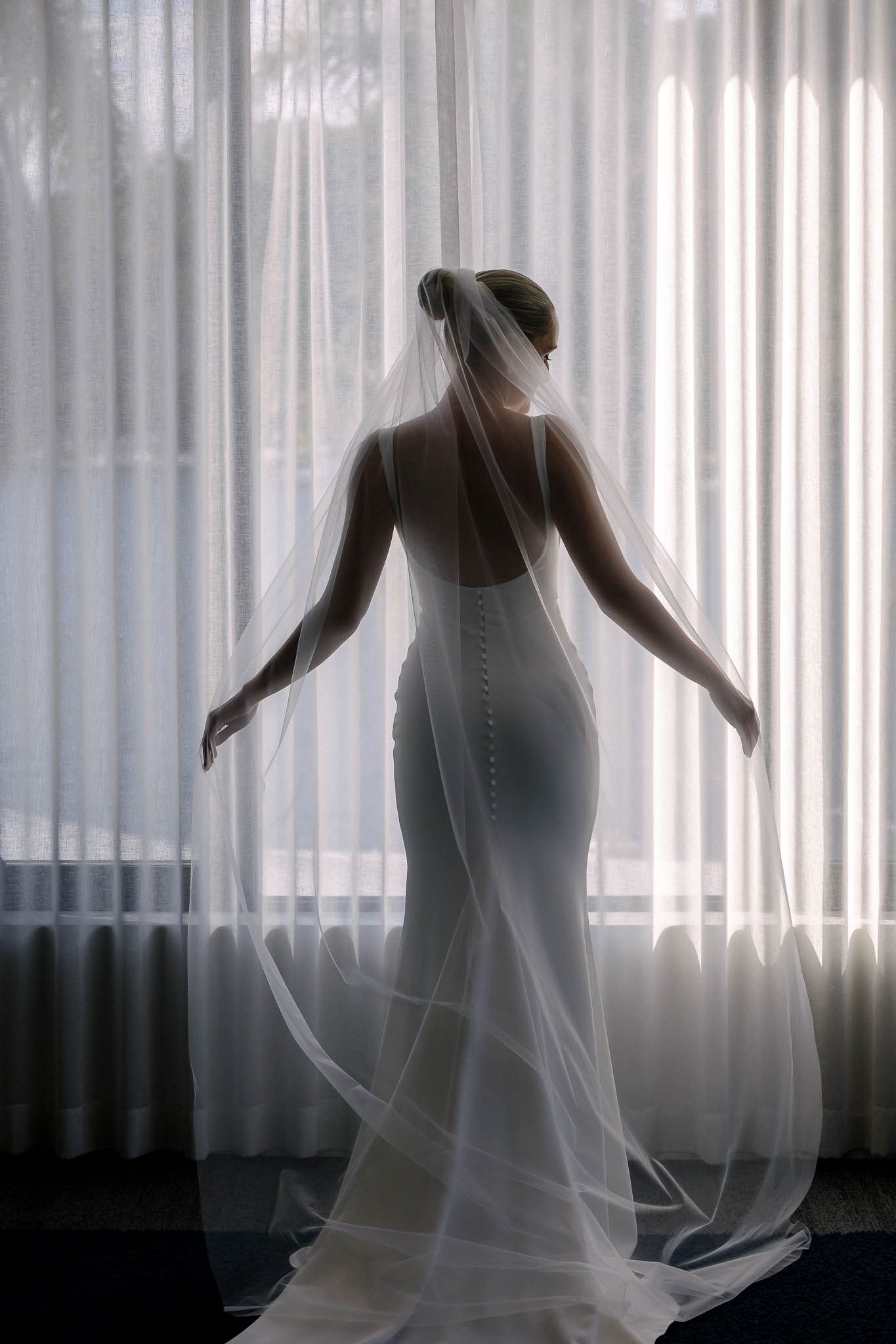 bride getting ready at pasadena sydney, standing next to the window in the long slim wedding dress.