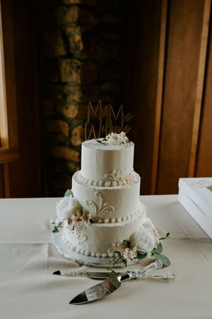 Classic white tiered wedding cake with delicate piping and floral accents.