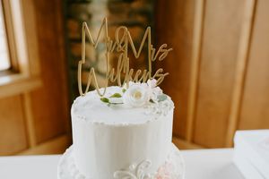 White wedding cake with elegant piping detail and 'Mr & Mrs' gold cake topper.
