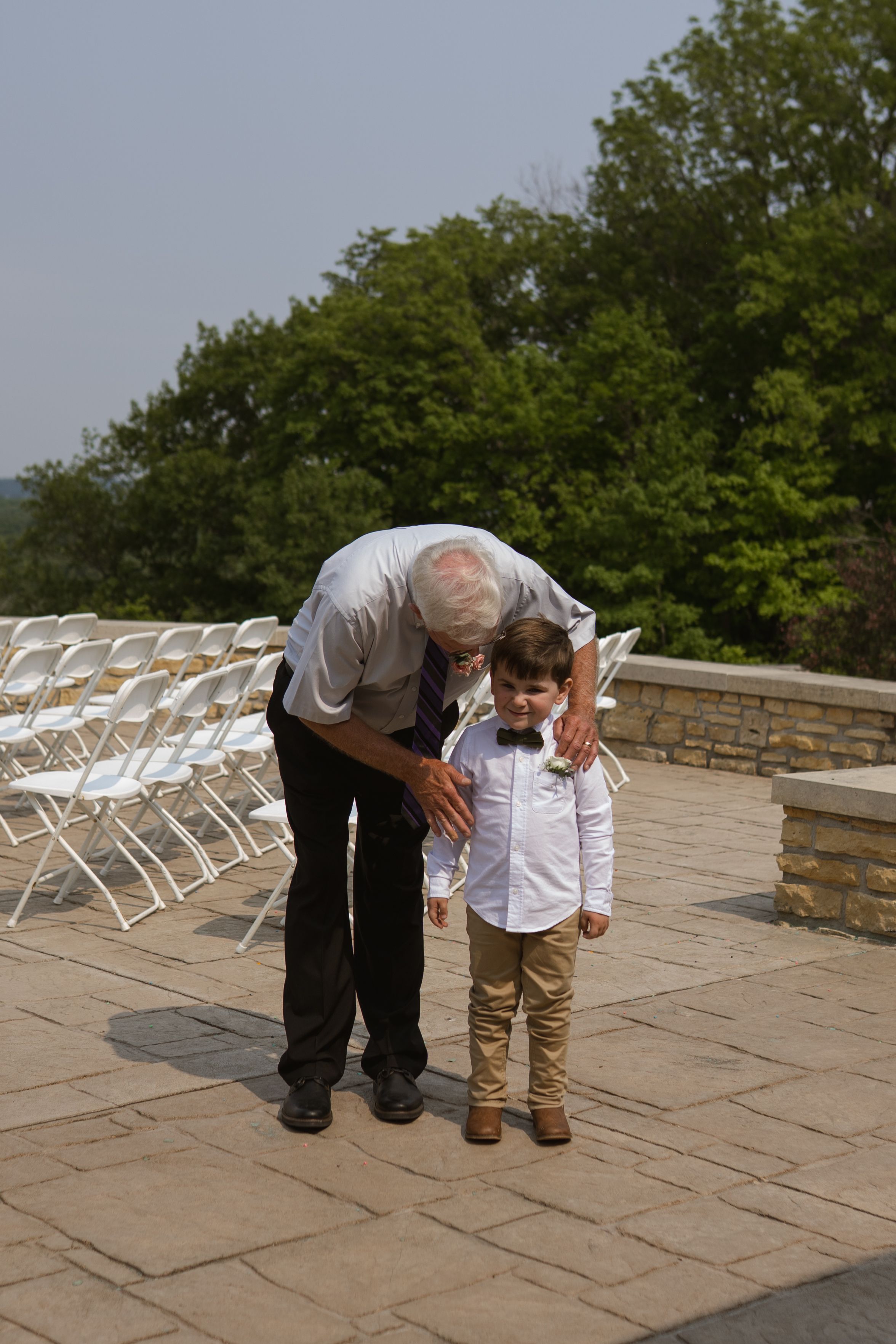 Sweet moment between generations at outdoor wedding venue with white chairs.