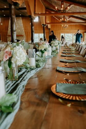 Wedding reception table decorated with white floral centerpieces and rustic wooden details.