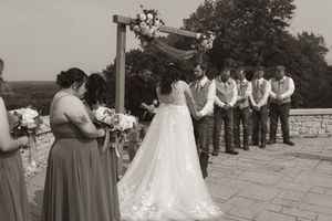 Wedding ceremony setup with white chairs and guests in black and white photography.