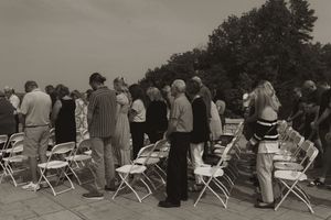 Outdoor wedding ceremony seating arrangement with white folding chairs in monochrome.