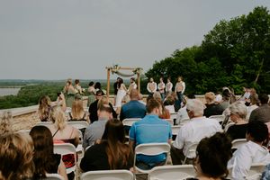 Outdoor wedding ceremony setup with guests seated overlooking a scenic landscape.