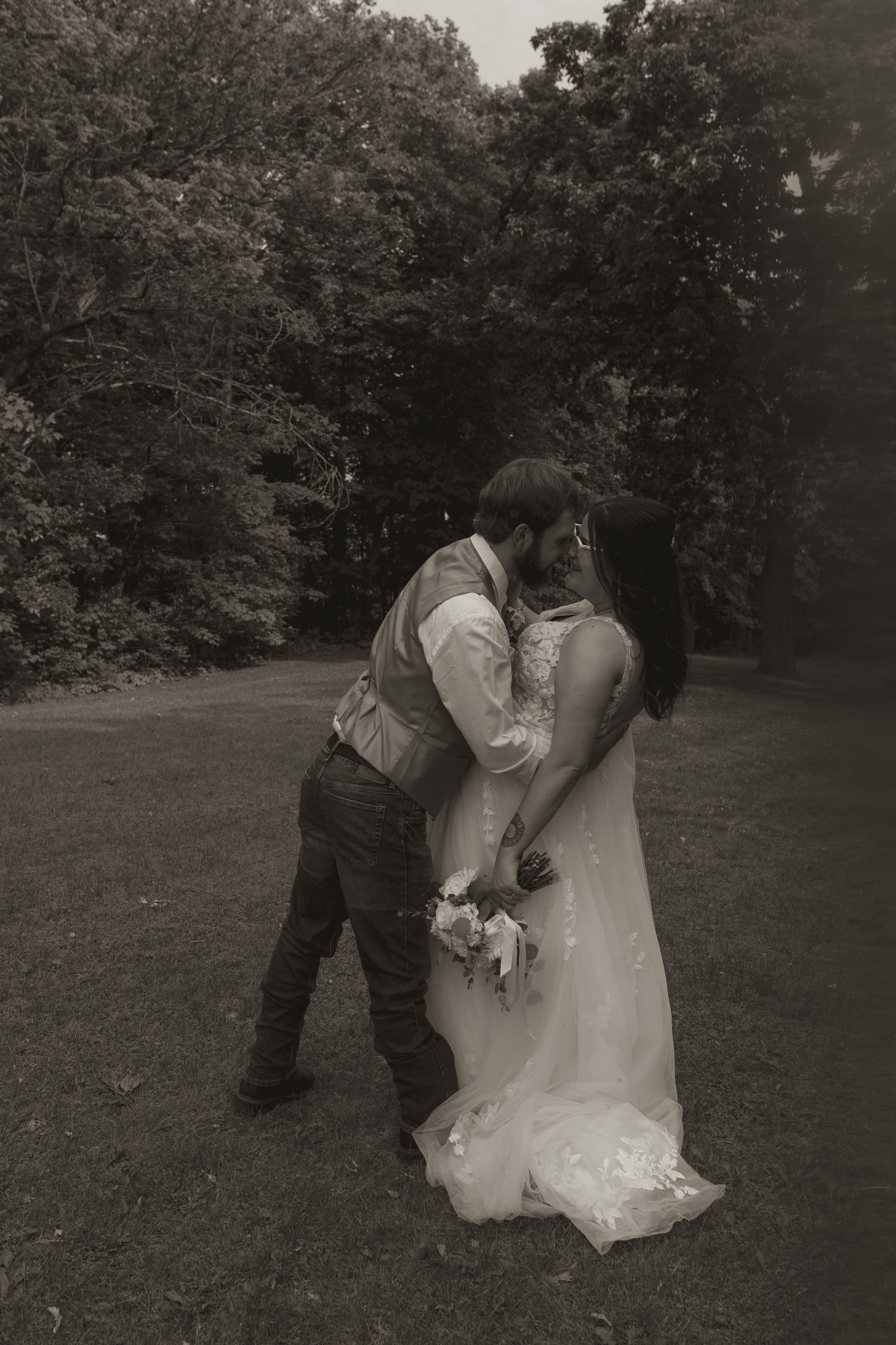 Romantic black and white portrait of couple sharing intimate moment in garden setting.