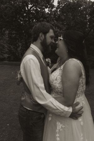 Intimate black and white portrait of newlyweds embracing during outdoor wedding.