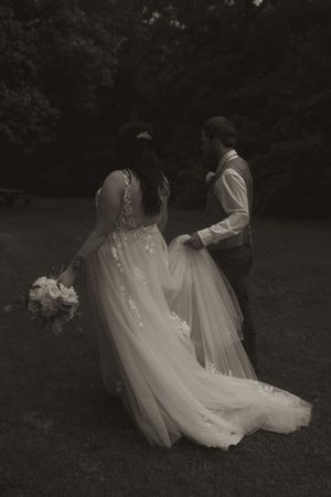 Artistic black and white photo of couple's romantic moment in garden setting.