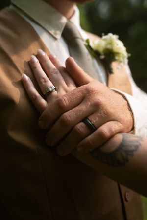 Close-up of wedding rings and hands in natural lighting showing fine details and textures.