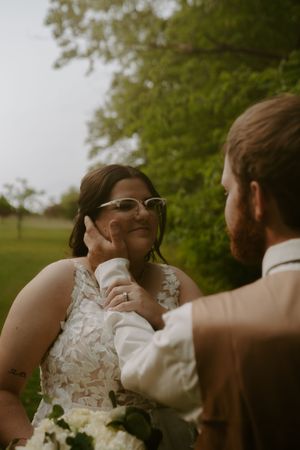 A tender wedding moment captured between newlyweds in a lush outdoor garden setting.