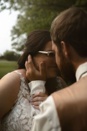 Intimate wedding portrait showing a couple's emotional embrace against green foliage.