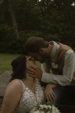 Romantic wedding portrait with white floral bouquet and lace dress details in natural setting.