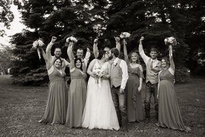 Wedding party celebrates with joyful poses outdoors in formal attire.