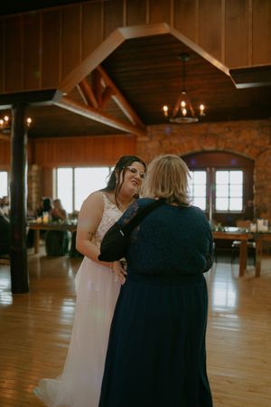 A tender moment shared during a wedding dance in a rustic reception venue with wooden beams.