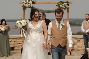 A joyful wedding celebration moment on a stone patio with bridesmaids in sage green dresses.