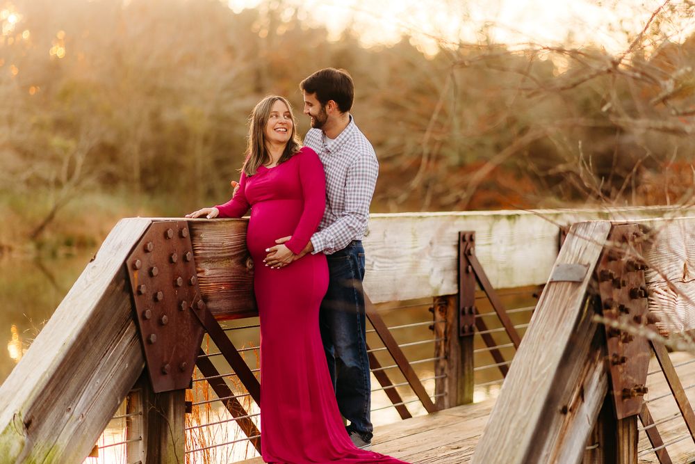A couple wearing coordinated outfits share romantic moments on a rustic wooden bridge during a golden sunset photoshoot.