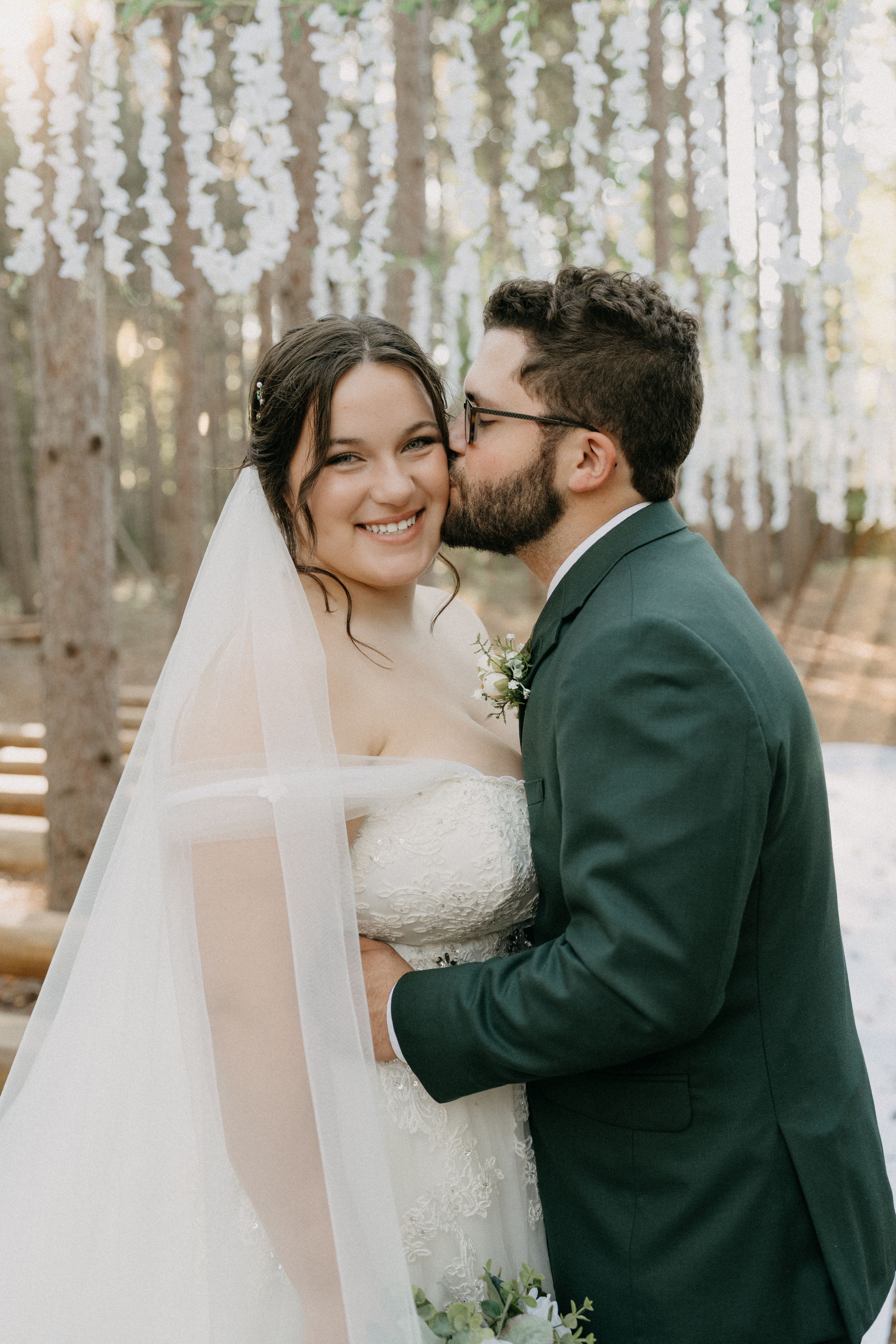 A romantic winter wedding moment captured in a snowy forest setting.