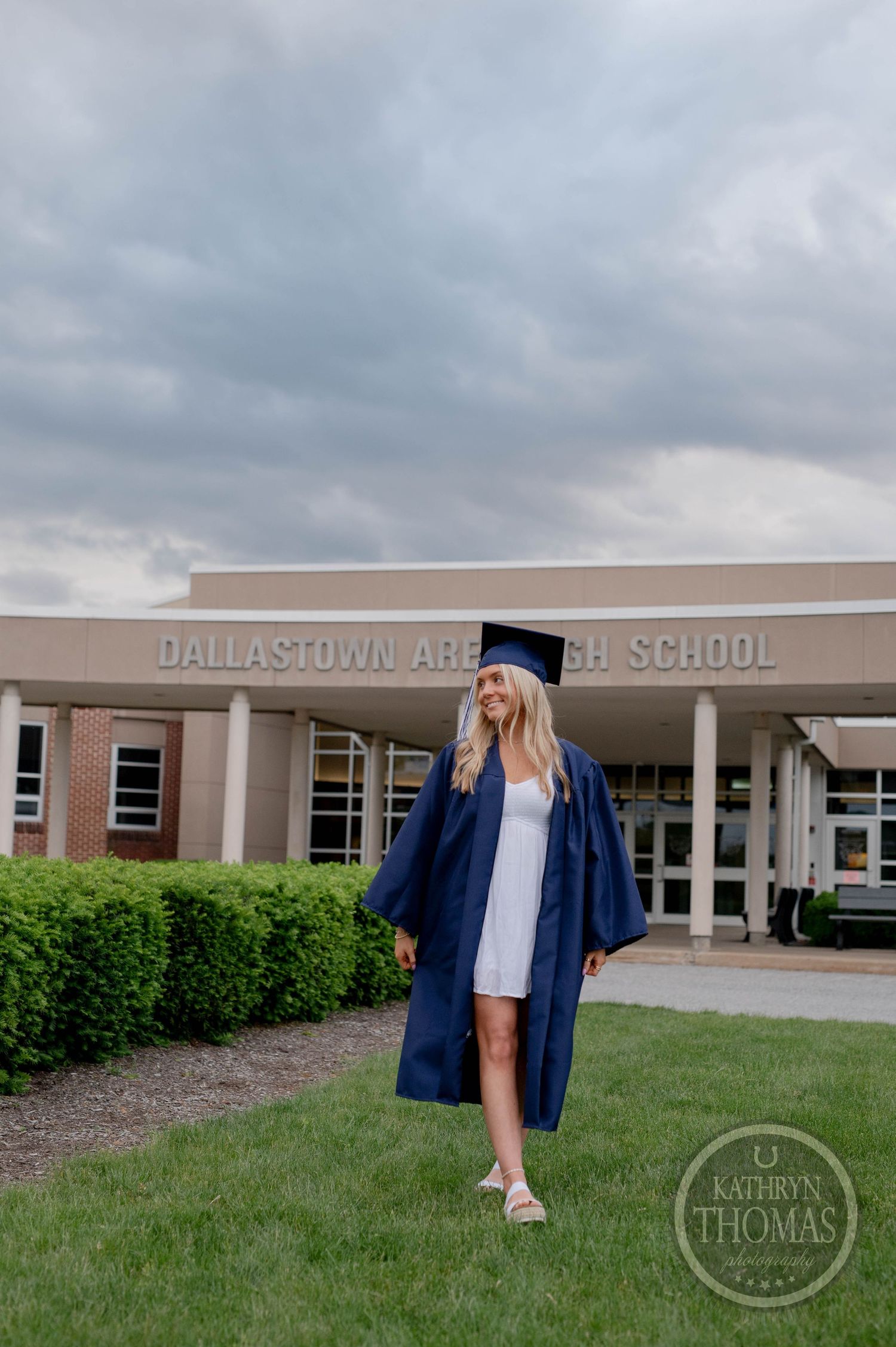A graduation portrait shoot outside Dallastown Area High School with a graduate in blue cap and gown.