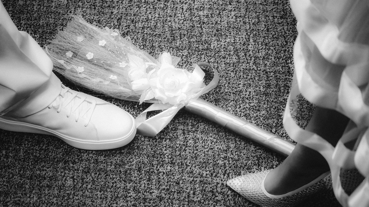 A white broom lies between two pairs of white shoes by Ellucid Design Studio LLC Great Lakes Bay Region