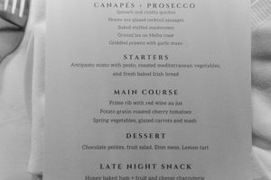 A black and white menu showing canapés, prosecco, starters, main course, dessert and late night snack offerings.